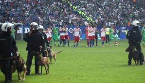 Die Spieler des HSV und von Borussia Mönchengladbach warten während der rund zehnminütigen Spielunterbrechung darauf, dass es weitergehen kann.